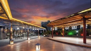 An outdoor dining area with tables and chairs, covered by a wooden structure, and illuminated by ambient lighting. - Ronzou International Hotel (Rong County)