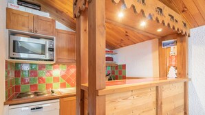 Una cocina de madera con microondas, lavavajillas y salpicadero de azulejos.
