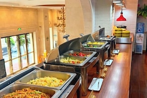 Un buffet proposant une variété de plats, un comptoir en bois et un luminaire suspendu rouge.