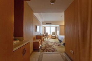 Ett hotellrum med en säng, ett skrivbord, en stol och utsikt över omgivningarna.