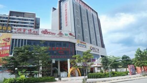 A modern hotel with a prominent vertical facade, large signage, and a parking lot in front. - Vienna International Hotel Zhongshan Torch Zone (Zhongshan)