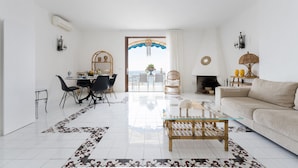 Un salon spacieux avec un canapé, un coin repas comprenant des chaises et une table, une cheminée et un balcon avec vue.