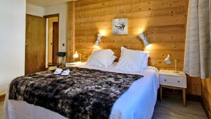 Une chambre à coucher avec une tête de lit en bois, un lit recouvert de draps blancs, deux lampes de chevet et un tableau encadré au mur.