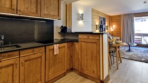 Une cuisine moderne avec des meubles en bois, un plan de travail noir et un coin repas comprenant une table et des chaises.