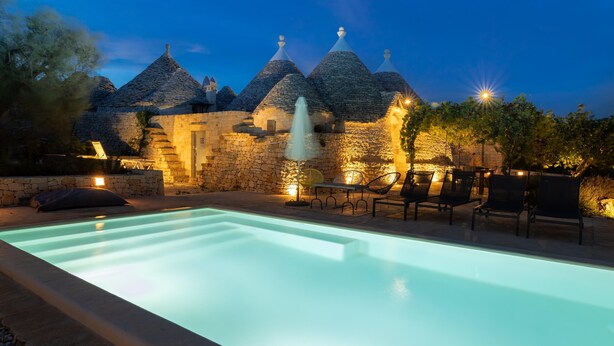 Ein Pool mit Steinarchitektur und Sitzgelegenheiten im Freien.