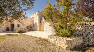 Un edificio de piedra con un patio, una pared de piedra y un árbol.