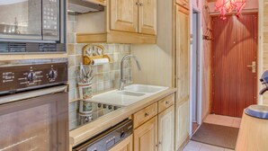 Una cocina con armarios de madera, una campana extractora de acero inoxidable, un lavamanos doble y un lavavajillas.