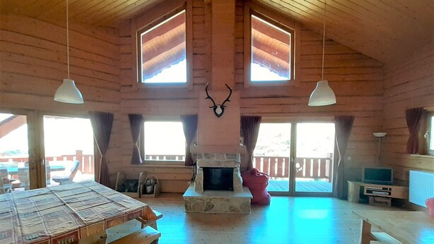 A spacious wooden cabin with a stone fireplace, large windows, and a wooden ceiling. - Spacious chalet 14 pers., fireplace, parking La Joue du Loup (La Joue du Loup)