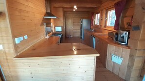 A wooden cabin kitchen with a central island, a stove, a refrigerator, and a microwave. - Spacious chalet 14 pers., fireplace, parking La Joue du Loup (La Joue du Loup)