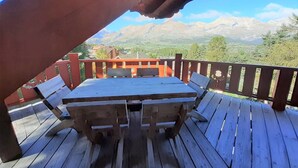 A wooden deck with a table and benches, overlooking a mountainous landscape. - Spacious chalet 14 pers., fireplace, parking La Joue du Loup (La Joue du Loup)