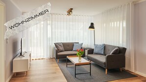 A modern living room with a sofa, a coffee table, and a lamp. - Spacious vacation apartment in a central and quiet location with terrace (Büsum)