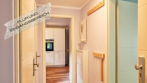 A hallway with white cabinets, a wooden floor, and a door leading to a kitchen area. - Spacious vacation apartment in a central and quiet location with terrace (Büsum)