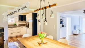 A modern kitchen with white cabinets, a wooden dining table with chairs, and a vase of flowers. - Spacious vacation apartment in a central and quiet location with terrace (Büsum)