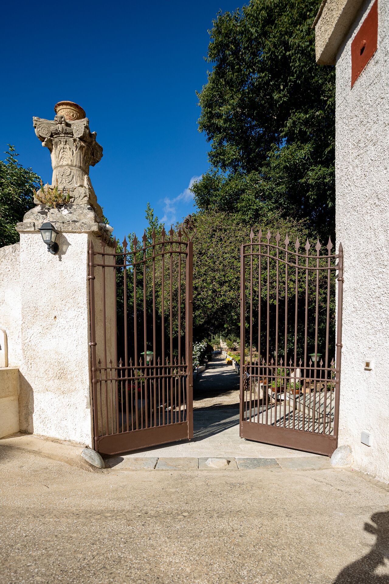 Una entrada protegida con un pilar de piedra y una verja de metal.