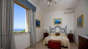 Um quarto com uma cama, mesa de cabeceira, cômoda e janela com cortinas.