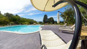 Uma área à beira da piscina com espreguiçadeiras e um toldo.