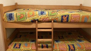 Un lit superposé avec une courtepointe aux couleurs vives et une échelle en bois.