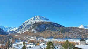 Un pueblo de montaña con edificios nevados y un campanario de iglesia destacada.
