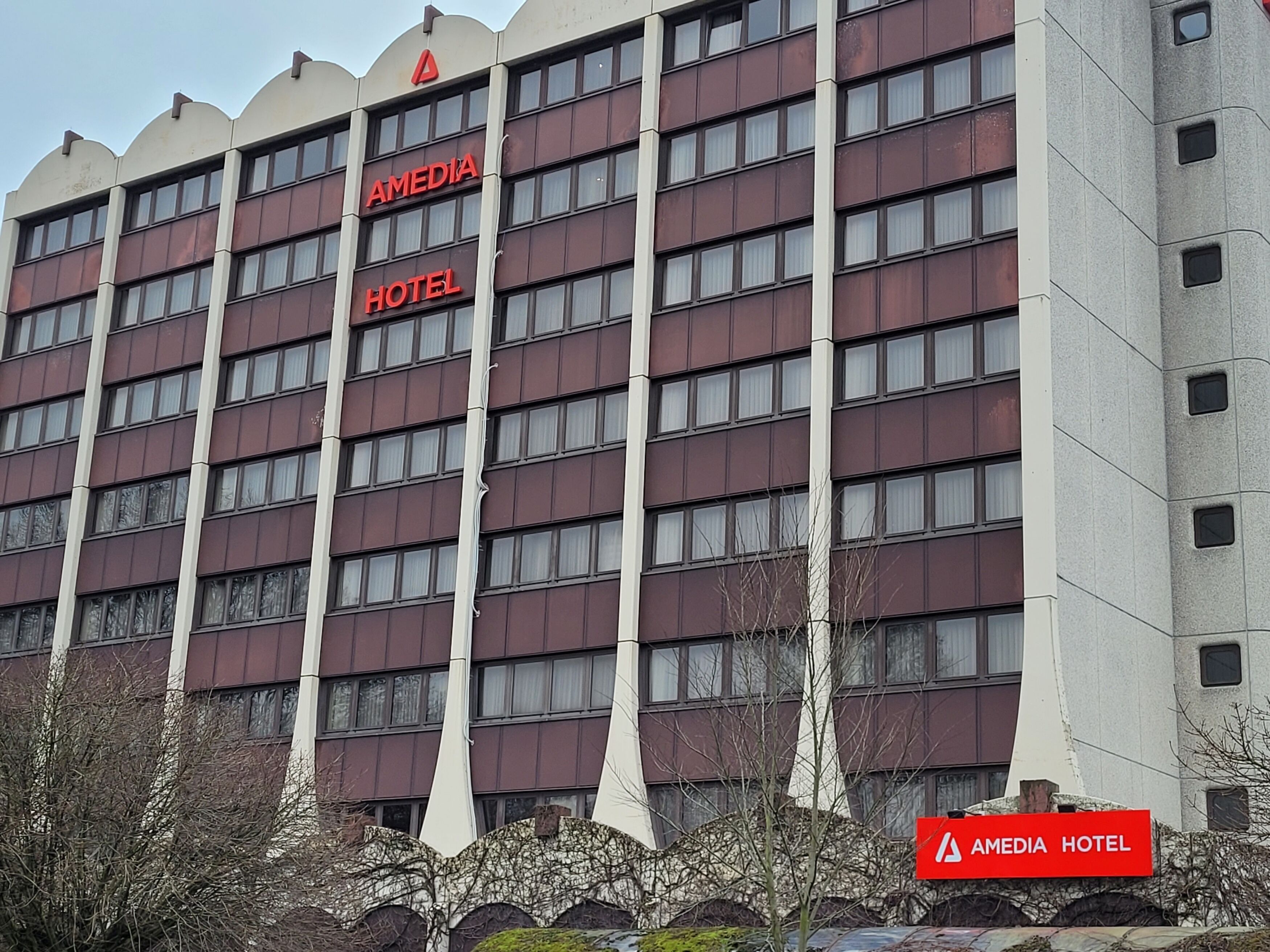 A multi-story hotel with a prominent red sign reading "AMEDIA HOTEL."