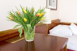 A glass vase with yellow and red tulips on a wooden table in a hotel room. - City Hotel Siegen (Siegen)