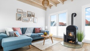 Una sala de estar con un sofá azul, una mesa de centro de vidrio, una chimenea y cuadros en la pared.