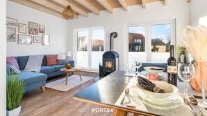 Una sala de estar moderna con un sofá, una chimenea y un comedor con una mesa dispuesta para dos.