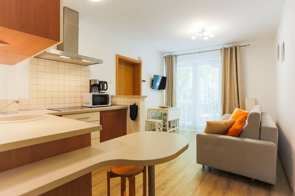 Una cocina moderna con una isla central, un comedor con mesa y sillas, y una sala de estar con sofá y televisor de pantalla plana.