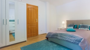 A bedroom with a bed, a wardrobe, a wooden door, and a nightstand with a lamp. - Apartamenty Swinoujscie - Villa Teresa (Swinoujscie)
