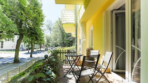 An outdoor seating area with tables and chairs, a yellow building, and a street view. - Apartamenty Swinoujscie - Villa Teresa (Swinoujscie)