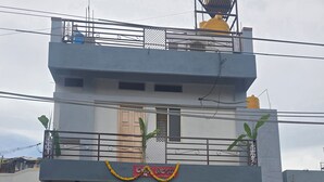 A two-story building with a balcony, potted plants, and a parked car. - Private Two bedrooms flat in Hampi (Hampi)