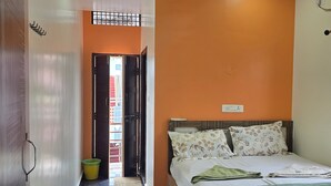 A bedroom with a bed, a ceiling fan, and a view through an open door. - Private Two bedrooms flat in Hampi (Hampi)