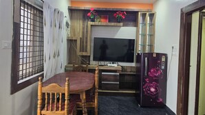 A compact kitchen with a dining table, chairs, a refrigerator, and a television. - Private Two bedrooms flat in Hampi (Hampi)