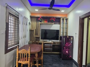 A compact kitchen with a dining table, chairs, a refrigerator, and a television. - Private Two bedrooms flat in Hampi (Hampi)
