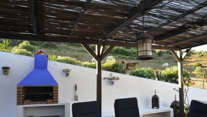 An outdoor patio with a brick oven, seating, and a decorative lantern.