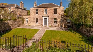 A stone building with a central entrance, two side wings, and a well-maintained lawn. - Beautiful Georgian property enjoying a quiet location. Sleeps 10. (Edinburgh)
