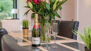 A table with a bottle of Codorniu wine, two empty glasses, and a vase with roses and green foliage. - Beautiful Georgian property enjoying a quiet location. Sleeps 10. (Edinburgh)
