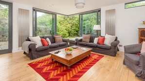 A modern living room with two grey sofas, a wooden coffee table, and a red and orange rug. - Beautiful Georgian property enjoying a quiet location. Sleeps 10. (Edinburgh)