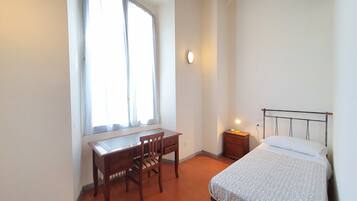 A bedroom with a bed, a desk, and a chair.