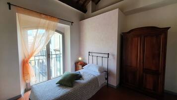 Una camera da letto con un letto, un comodino, un'armadietto in legno e una finestra con tende leggere.
