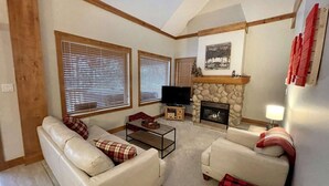 A living room with two sofas, a coffee table, a fireplace, and a television. - Alpine Bliss Awaits: Beautiful Mountain Home with Hot Tub (Kimberley)
