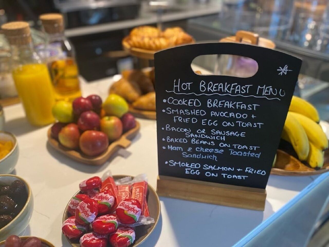 Una exhibición de desayuno con un cartel que enumera opciones como desayuno completo, aguacate machacado, tocino y más.