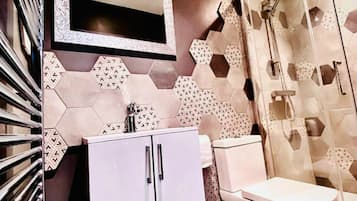A bathroom with a shower, toilet, and cabinet.