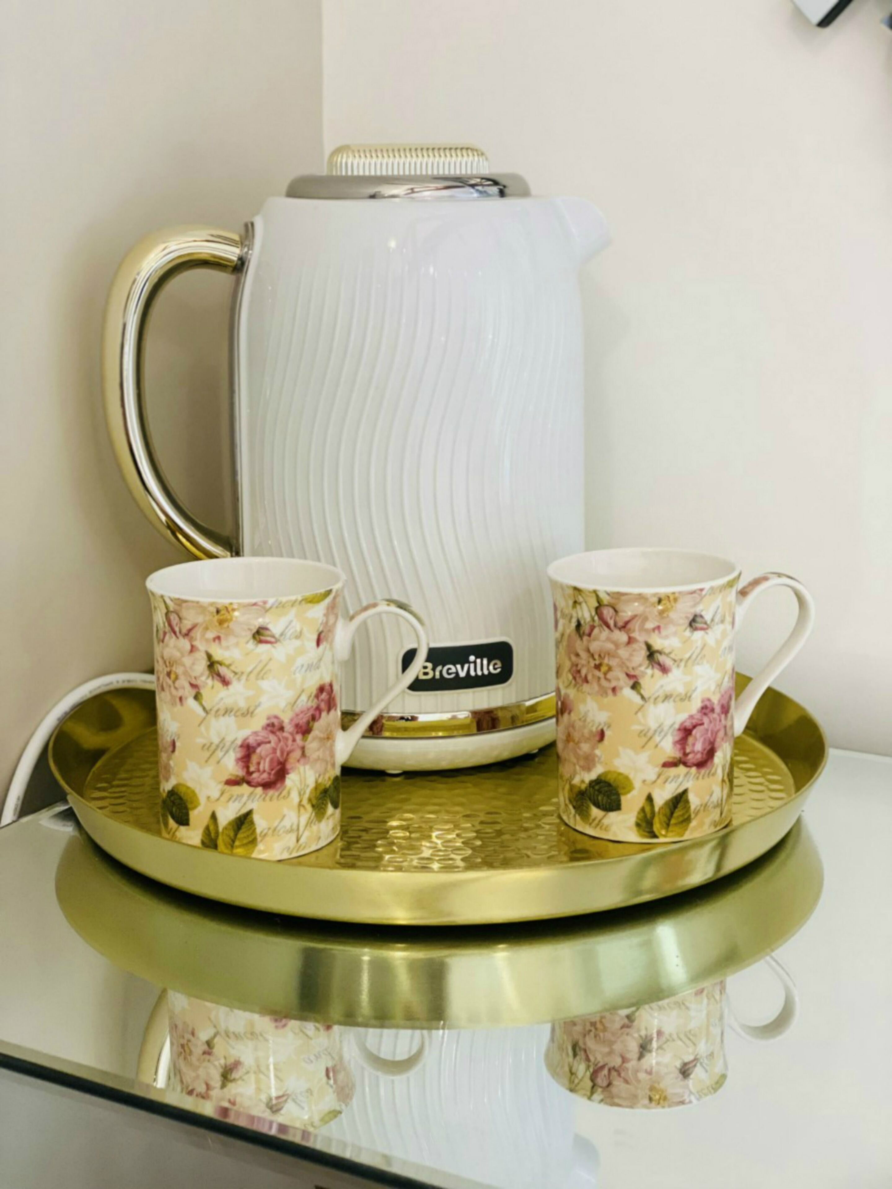 A Breville coffee maker on a tray with two matching floral mugs.