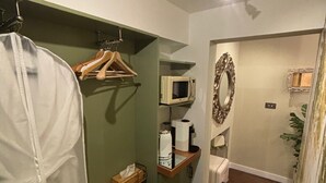 Ein Badezimmer mit Dusche, Toilette, Waschbecken, Spiegel und einer Mikrowelle.