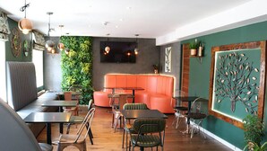 Ein modernes Interieur mit grüner Wand, orangefarbenen Sitzgelegenheiten und Holzböden.