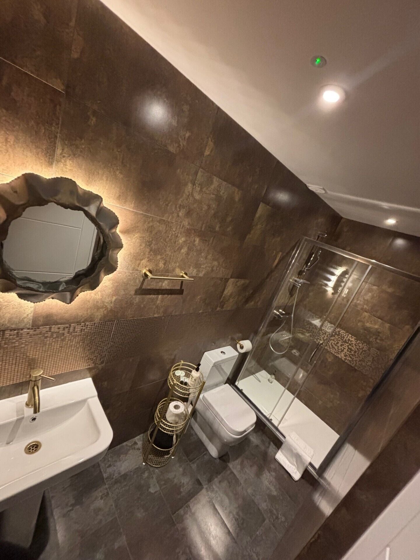 A modern bathroom with a large mirror, a sink, a toilet, and a shower area.