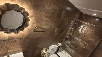 A modern bathroom with a large mirror, a sink, a toilet, and a shower area.