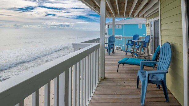 A wooden deck with blue chairs and a table overlooking the ocean. - Ocean Dunes 2123 (Kure Beach)