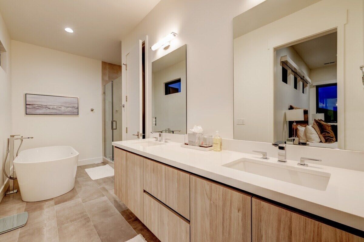 A modern bathroom with a freestanding bathtub, a large vanity with a double sink, and a large mirror.