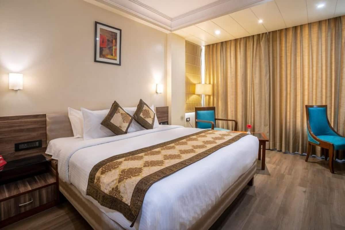 Een hotelkamer met een groot bed, twee stoelen, een bureau en een lamp.